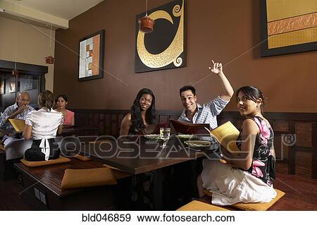 Stock Photo - Multi-ethnic friends at restaurant. Fotosearch