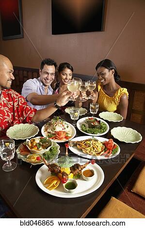 Stock Photography - Multi-ethnic friends toasting at restaurant. Fotosearch