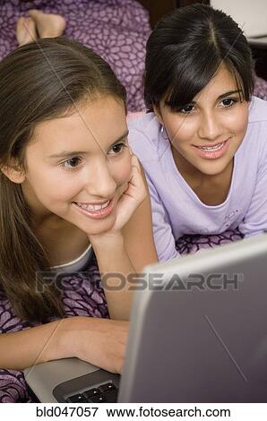 Stock Photo - Multi-ethnic girls looking at laptop. Fotosearch