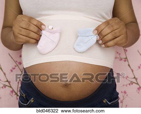 Stock Image - Pregnant African American woman holding booties. Fotosearch