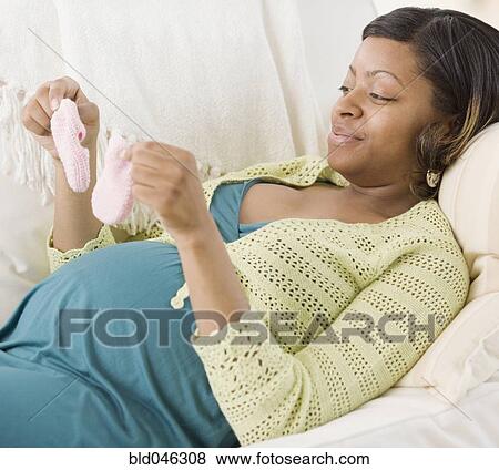 Stock Photo - Pregnant African American woman holding booties. Fotosearch