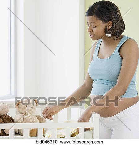 Pregnant African American woman looking at crib View Large Photo Image Stock Image - Pregnant African American woman looking at crib. Fotosearch