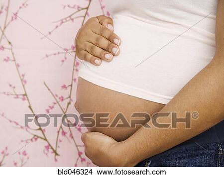 Picture - Pregnant African American woman with hands on belly. Fotosearch