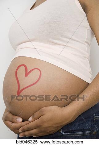 Stock Photography - Pregnant African American woman with heart on belly. Fotosearch