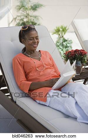 Stock Image - Senior African American woman reading book. Fotosearch
