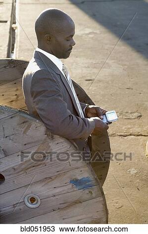Stock Image - African American businessman dialing cell phone. Fotosearch