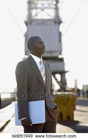 Stock Photo - African American businessman holding laptop. Fotosearch