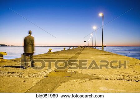 Stock Photo - African American businessman walking on commercial pier. Fotosearch
