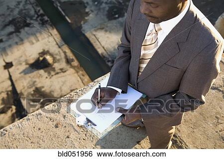 Stock Photograph - African American businessman writing on clipboard. Fotosearch