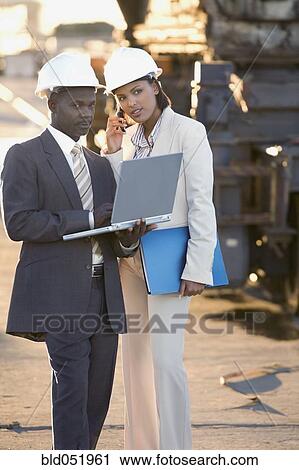 Stock Image - African American businesspeople wearing hardhats. Fotosearch