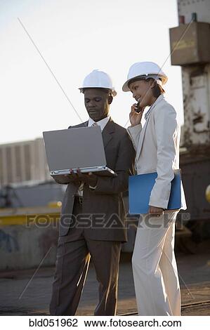 Stock Image - African American businesspeople wearing hardhats. Fotosearch