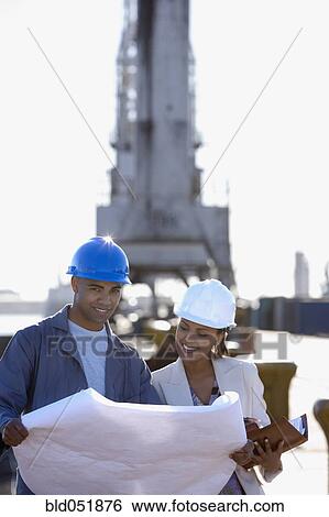 Stock Photograph - African American businesswoman and construction worker with blueprints. Fotosearch