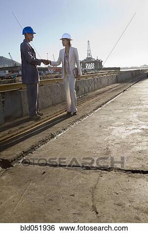 Stock Photograph - African American businesswoman and construction worker shaking hands. Fotosearch