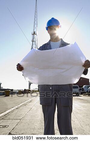 Stock Image - African American construction worker holding blueprints. Fotosearch