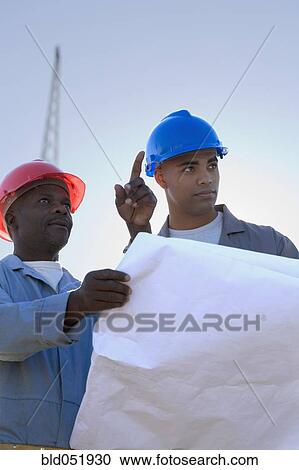 Stock Image - African American construction workers with blueprints. Fotosearch