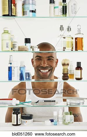 Stock Image - African American man looking in medicine cabinet. Fotosearch