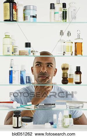 Stock Image - African American man looking in medicine cabinet. Fotosearch