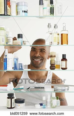 Stock Photo - African American man looking in medicine cabinet. Fotosearch