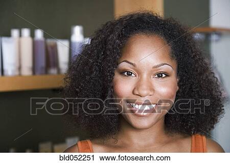 Stock Image - African American woman in front of hair care products. Fotosearch