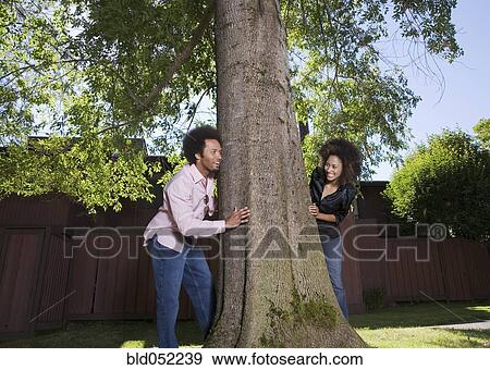 Stock Photo - African couple peeking around tree. Fotosearch