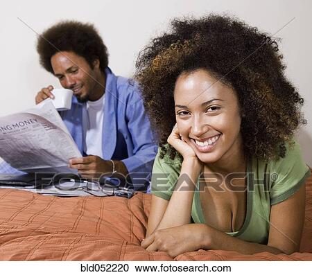 Stock Image - African couple relaxing in bed. Fotosearch