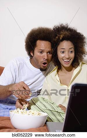 Stock Photo - African couple watching movie on laptop. Fotosearch
