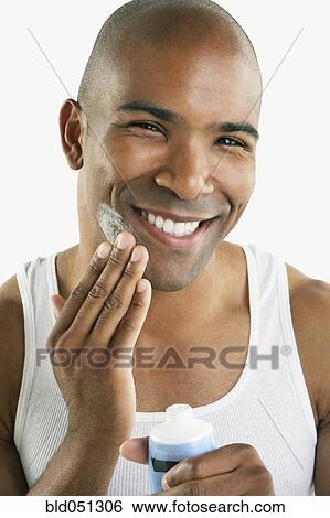 Stock Photograph - African man applying face cream. Fotosearch