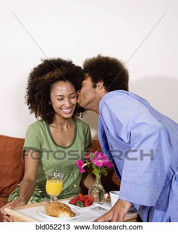 Stock Image - African man bringing breakfast in bed to wife. Fotosearch