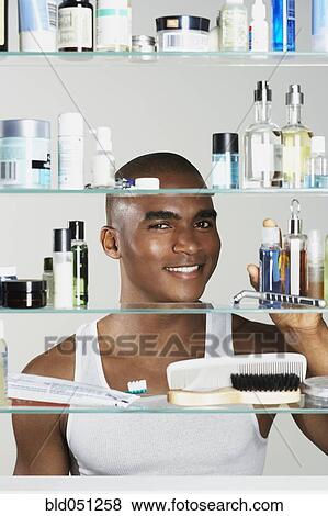 Stock Photo - African man looking in medicine cabinet. Fotosearch