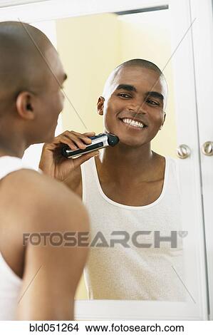 African man shaving with electric razor View Large Photo Image Picture - African man shaving with electric razor. Fotosearch
