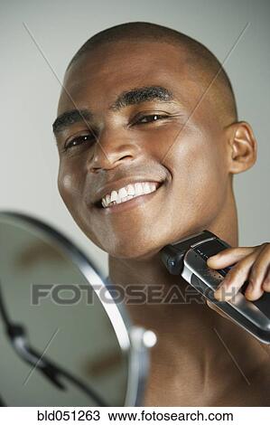 African man shaving with electric razor View Large Photo Image Stock Image - African man shaving with electric razor. Fotosearch