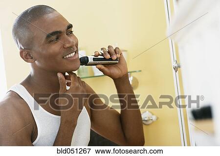African man shaving with electric razor View Large Photo Image Stock Photo - African man shaving with electric razor. Fotosearch