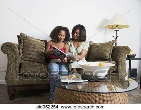 Picture - African mother and adult daughter reading magazine. Fotosearch