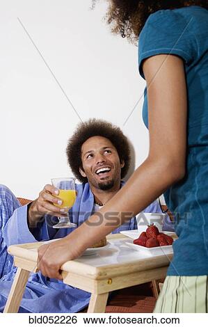 Stock Photograph - African woman bringing breakfast in bed to husband. Fotosearch