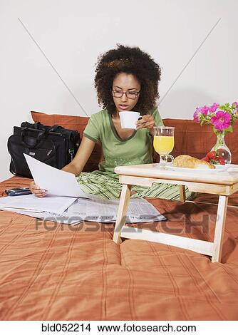 Picture - African woman eating breakfast in bed. Fotosearch