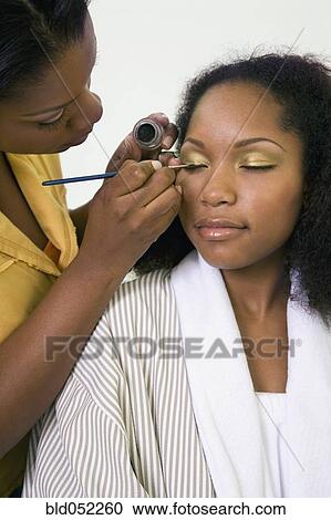 Stock Image - African woman having makeup applied. Fotosearch