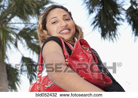 Stock Image - African woman holding handbag. Fotosearch