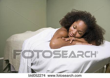 Picture - African woman laying on massage table. Fotosearch