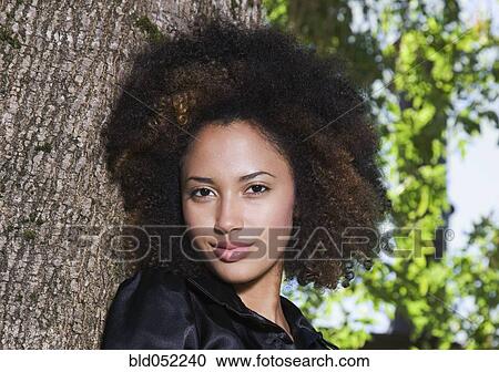 Stock Image - African woman leaning on tree. Fotosearch