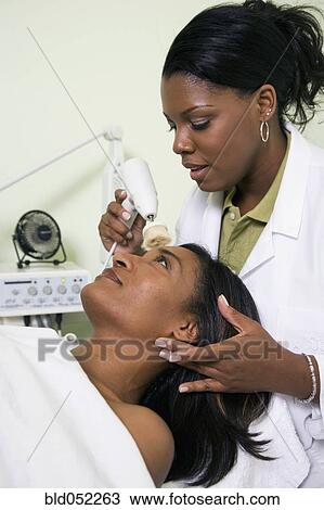 Stock Image - African woman receiving spa facial treatment. Fotosearch