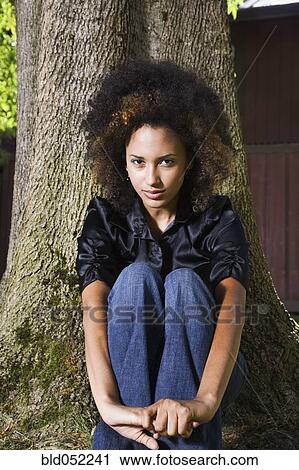 African woman sitting against tree View Large Photo Image Stock Image - African woman sitting against tree. Fotosearch