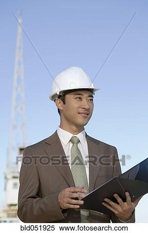 Stock Photography - Asian businessman wearing hardhat. Fotosearch