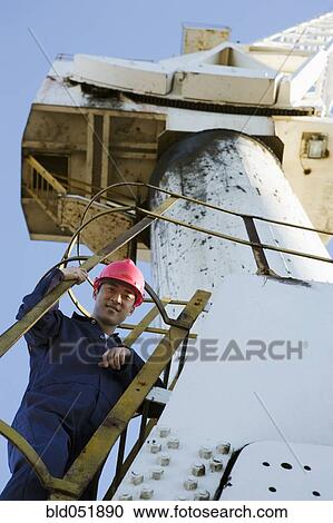 Stock Image - Asian male construction worker on crane. Fotosearch