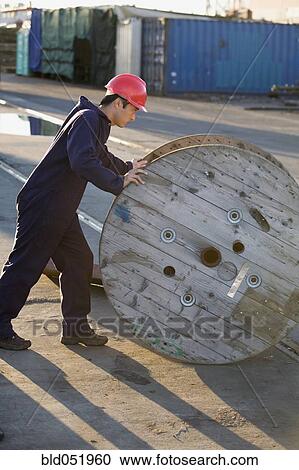 Asian male manual worker pushing wooden spool View Large Photo Image Stock Image - Asian male manual worker pushing wooden spool. Fotosearch