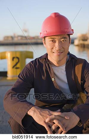 Picture - Asian male manual worker wearing hardhat. Fotosearch