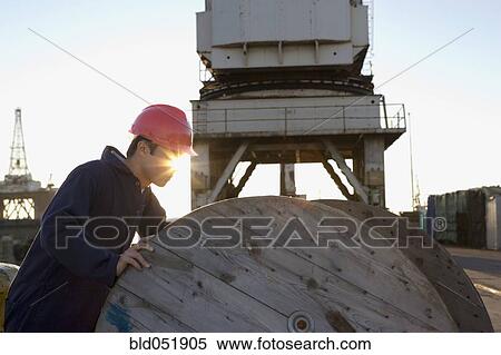 Asian manual worker pushing wooden spool View Large Photo Image Stock Photography - Asian manual worker pushing wooden spool. Fotosearch