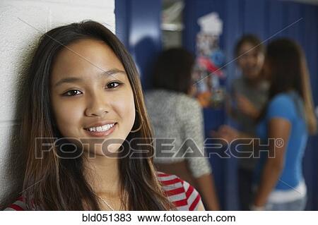 Stock Image - Asian teenaged girl in front of school lockers. Fotosearch
