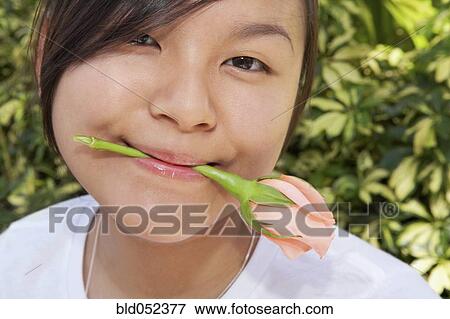 Asian woman holding flower in mouth View Large Photo Image Stock Photo - Asian woman holding flower in mouth. Fotosearch