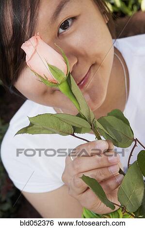 Asian woman holding flower View Large Photo Image Stock Photograph - Asian woman holding flower. Fotosearch