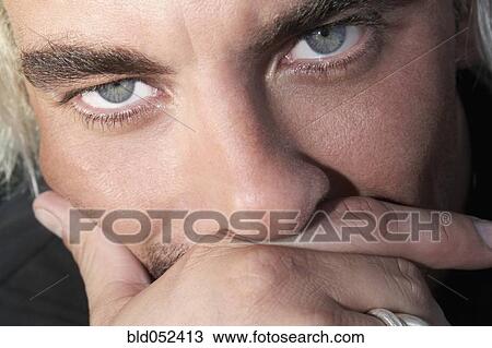 Stock Image - Close up of Hispanic man with hand on face. Fotosearch